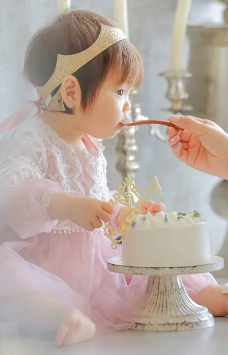 スプーンではじめてケーキを口にする赤ちゃん