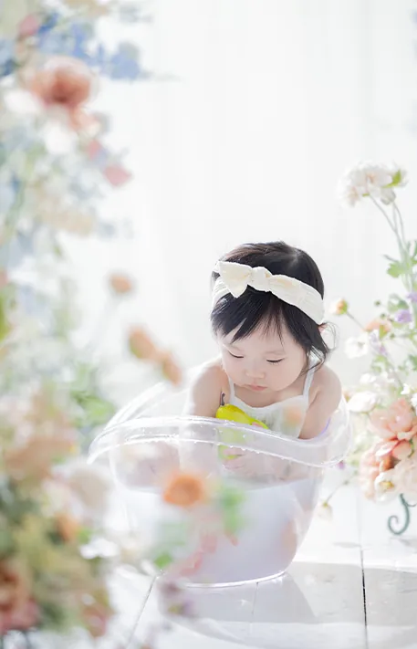 花に囲まれたミルクバスで静かに遊ぶ赤ちゃん